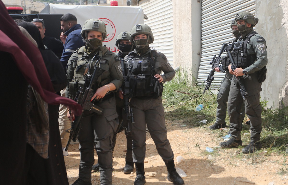 عائلات فلسطينية تنتظر عند نقطة تفتيش تابعة للجيش الإسرائيلي عند مدخل مخيم جنين للاجئين، قرب مدينة جنين في الضفة الغربية، لاستعادة ممتلكاتها من منازلها، 13 أبريل/نيسان 2026. صورة: محمد ناصر