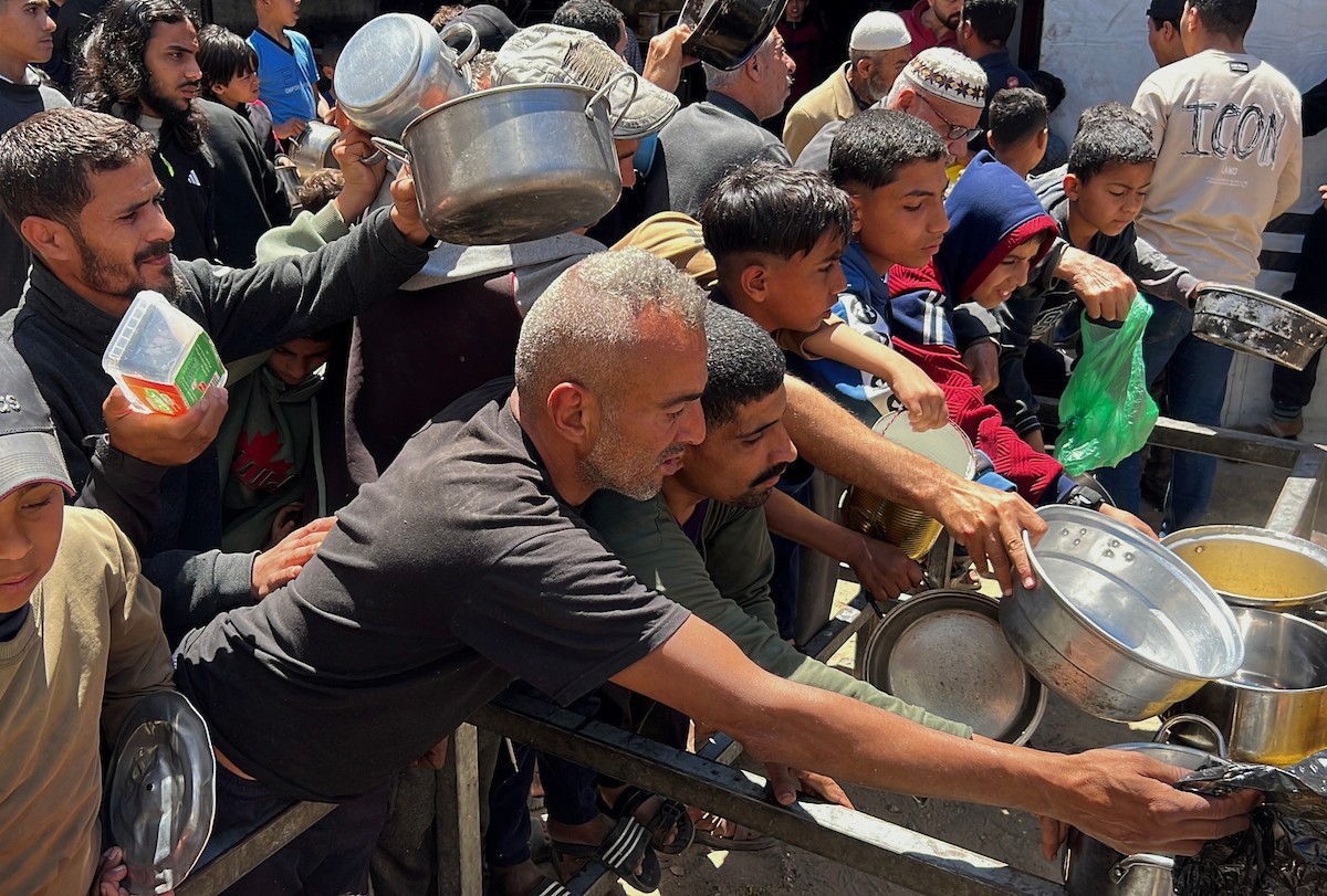 يتلقى فلسطينيون نازحون طعامًا من مطبخ خيري في مخيم النصيرات للاجئين وسط قطاع غزة، في 23 أبريل/نيسان 2026، (صورة: يوسف أبو وطفة)