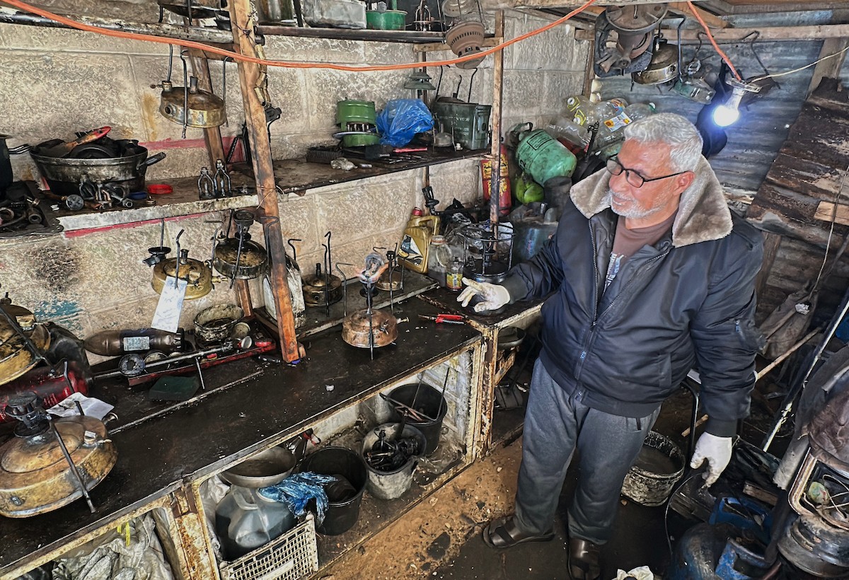 عادل عيسى، 63 عامًا، يُصلح مواقد الكيروسين القديمة في ورشته بمخيم الشاطئ، في مدينة غزة، صورة فوتوغرافية لهادي داود