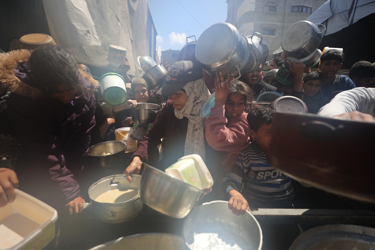 إحدى الجمعيات الخيرية توزع وجبات طعام على الفلسطينيين النازحين في مخيم النصيرات للاجئين، في ظل استمرار نقص الغذاء نتيجةً للسياسة الإسرائيلية المتعلقة بدخول المساعدات إلى مدينة غزة، في 11 أبريل/نيسان 2026. (تصوير: حسن جيدي)