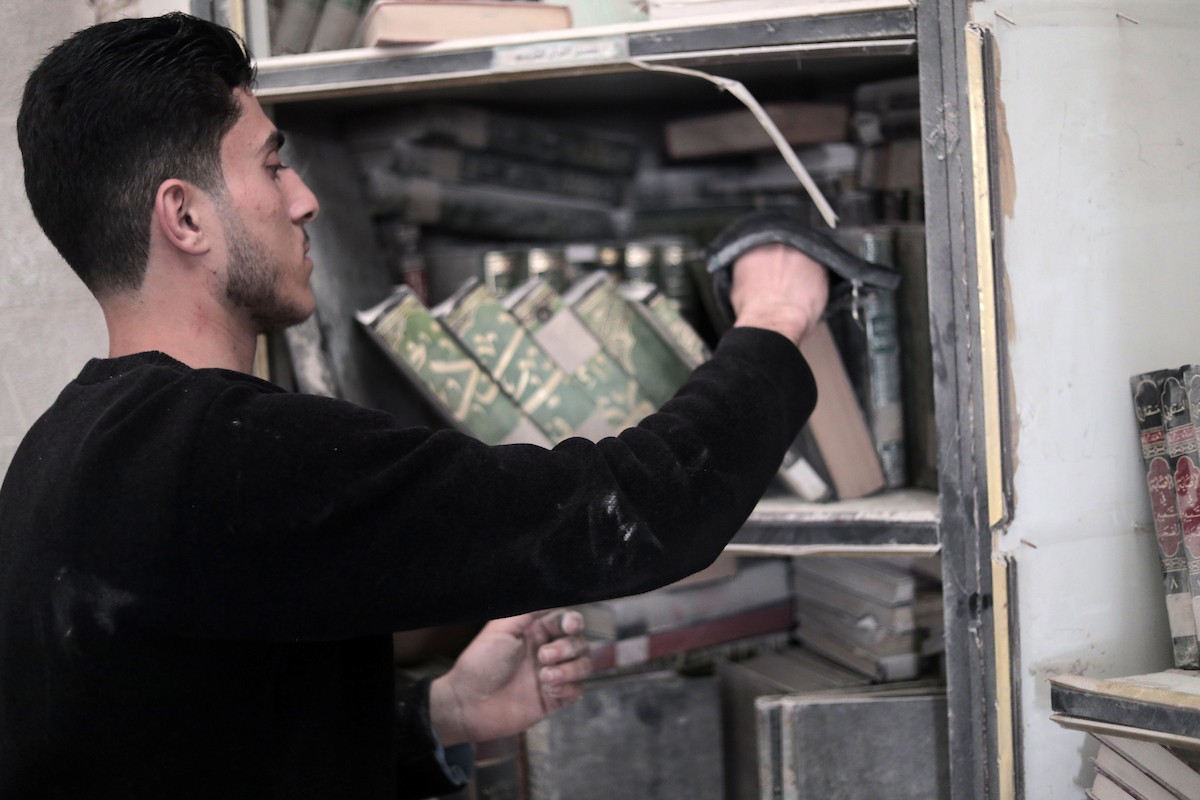 يتردد الشاب الفلسطيني كريم الخضري على مكتبة الجامع الكبير بغزة (الجامع العمري) في البلدة القديمة، شرق مدينة غزة، حيث يقوم بتنظيف الكتب وترتيبها بجدٍّ واجتهاد، 26 أبريل/نيسان 2026. تصوير: محمد الأسود