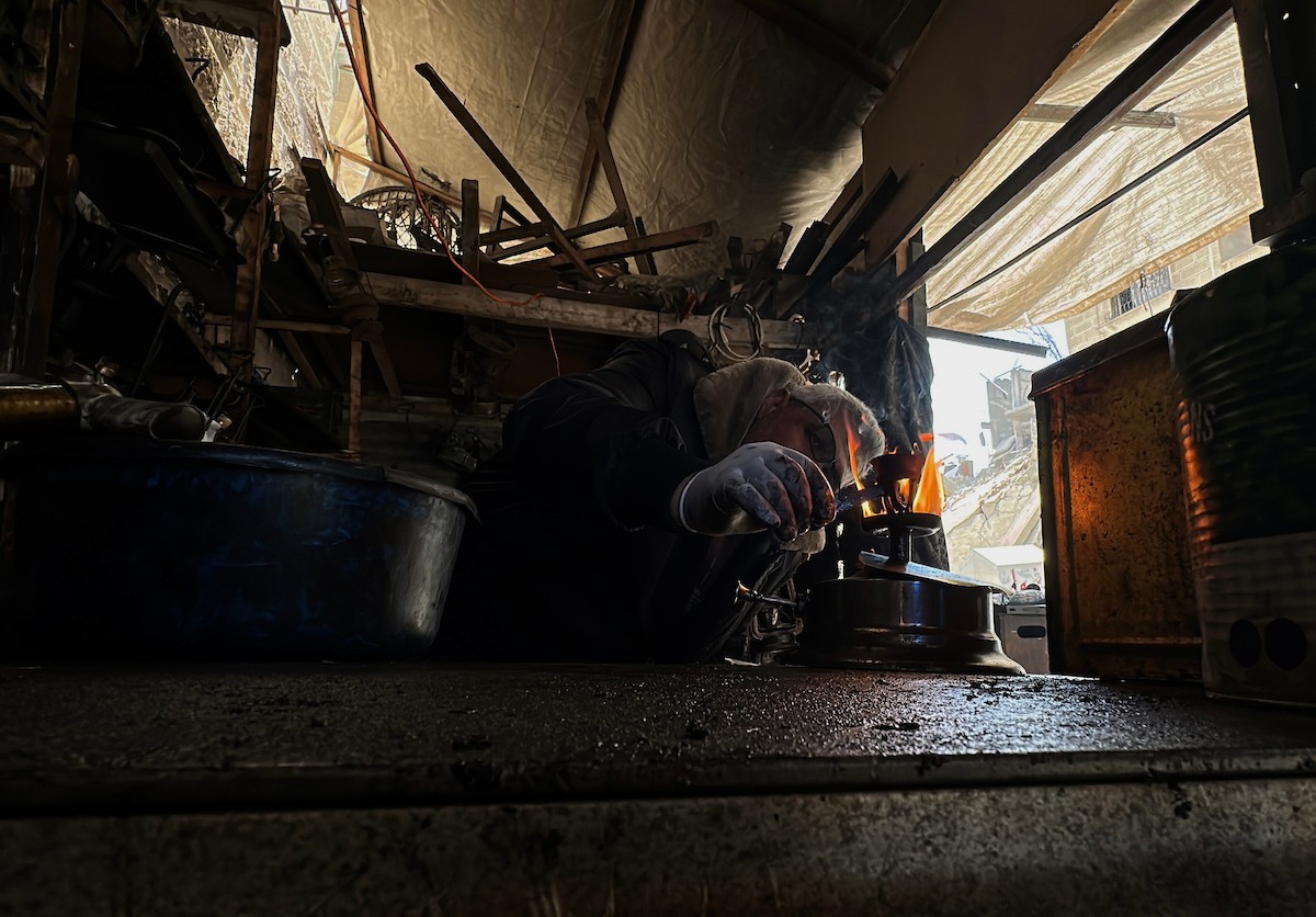 عادل عيسى، 63 عامًا، يُصلح مواقد الكيروسين القديمة في ورشته بمخيم الشاطئ، في مدينة غزة، صورة فوتوغرافية لهادي داود