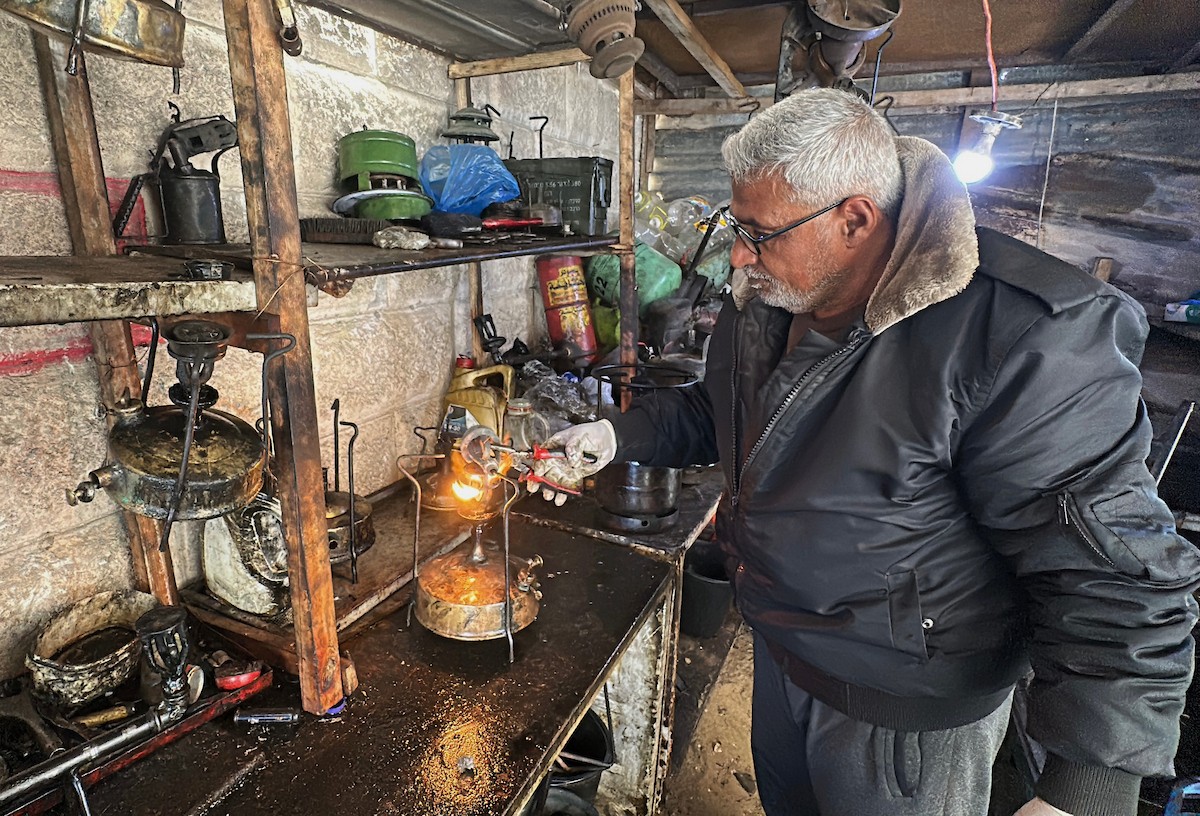 عادل عيسى، 63 عامًا، يُصلح مواقد الكيروسين القديمة في ورشته بمخيم الشاطئ، في مدينة غزة، صورة فوتوغرافية لهادي داود