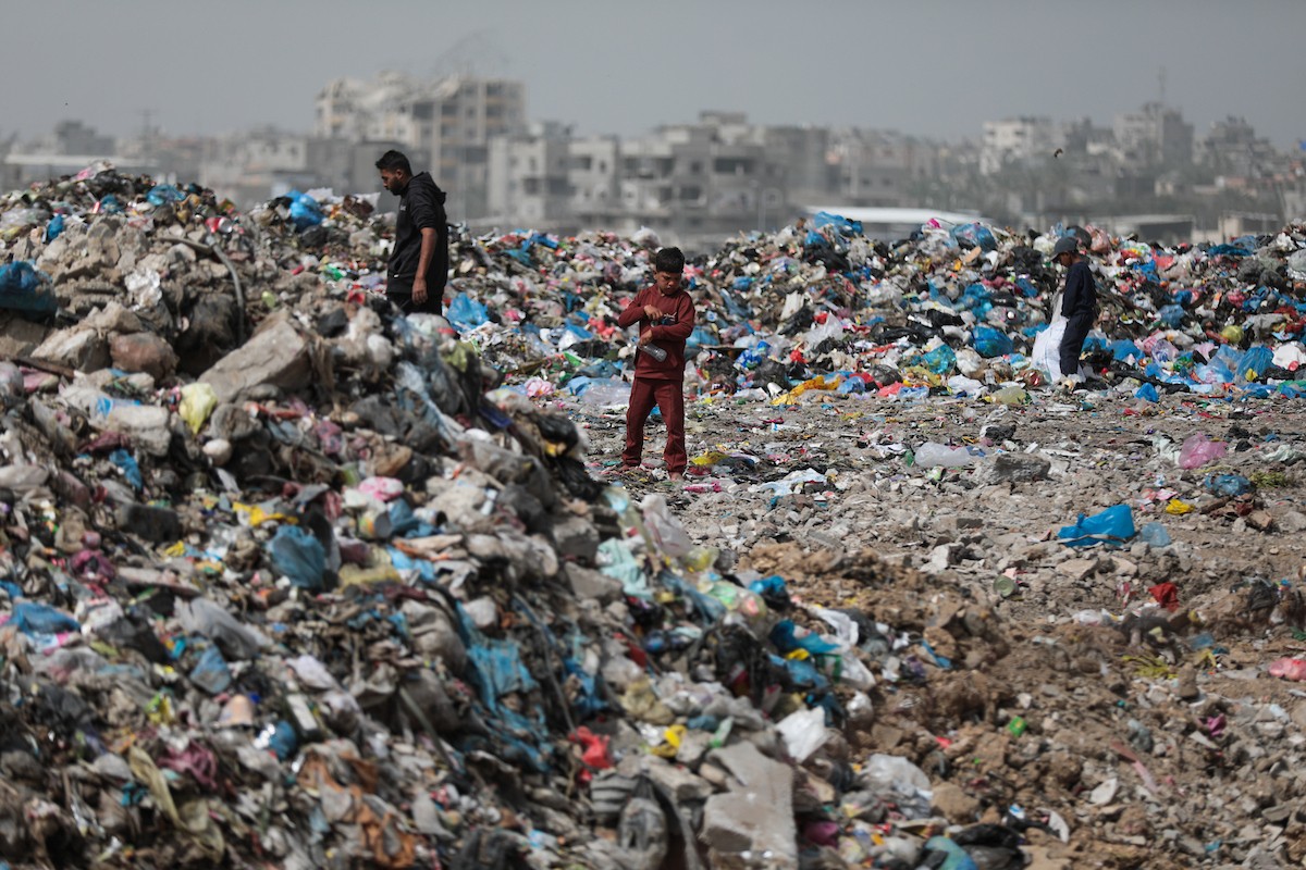 أطفال فلسطينيون يبحثون بين أكوام القمامة عن بقايا الطعام أو الألعاب في مكب نفايات بمخيم البريج للاجئين وسط قطاع غزة، في 4 أبريل/نيسان 2026، بالتزامن مع يوم الطفل الفلسطيني.(صورة: رمزي أبو عامر)