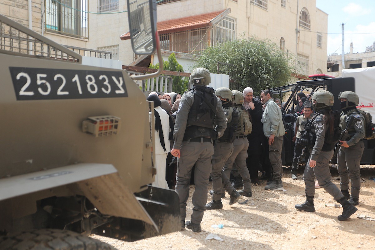 عائلات فلسطينية تنتظر عند نقطة تفتيش تابعة للجيش الإسرائيلي عند مدخل مخيم جنين للاجئين، قرب مدينة جنين في الضفة الغربية، لاستعادة ممتلكاتها من منازلها، 13 أبريل/نيسان 2026. صورة: محمد ناصر