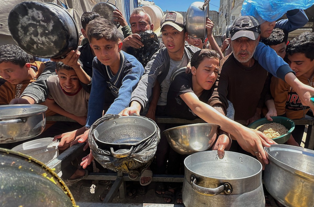 يتلقى فلسطينيون نازحون طعامًا من مطبخ خيري في مخيم النصيرات للاجئين وسط قطاع غزة، في 23 أبريل/نيسان 2026، (صورة: يوسف أبو وطفة)