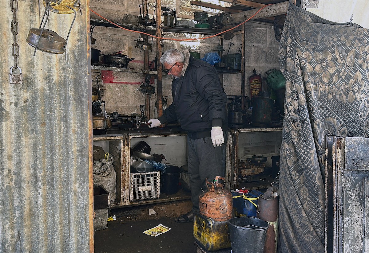 عادل عيسى، 63 عامًا، يُصلح مواقد الكيروسين القديمة في ورشته بمخيم الشاطئ، في مدينة غزة، صورة فوتوغرافية لهادي داود