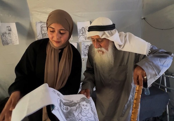 محمد زملط، رجل فلسطيني مسنّ اقتلعته الحرب من مخيم جباليا في شمال قطاع غزة، يحمل اليوم ريشته كوسيلة للبقاء، لا للفن فقط. في خيمته المتواضعة بمخيم البريج وسط القطاع، 12 أبريل/نيسان 2026، عدسة: يوسف أبو وطفة