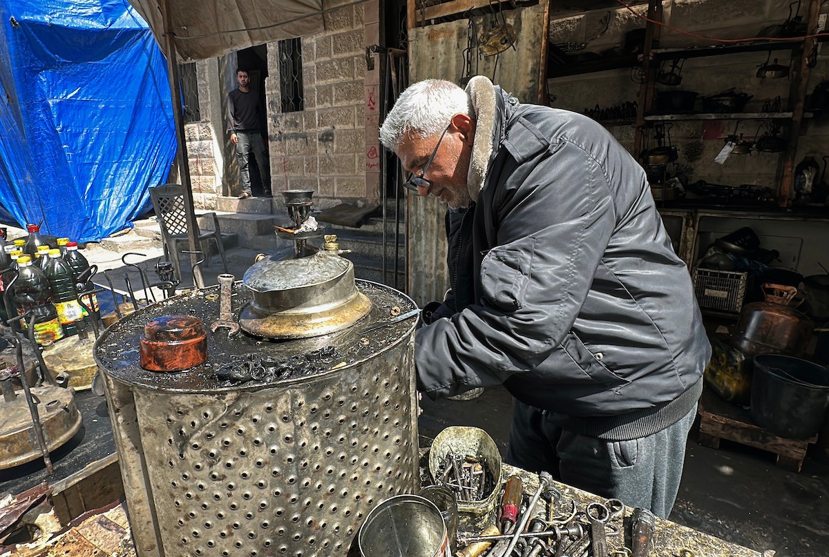 عادل عيسى، 63 عامًا، يُصلح مواقد الكيروسين القديمة في ورشته بمخيم الشاطئ، في مدينة غزة، صورة فوتوغرافية لهادي داود