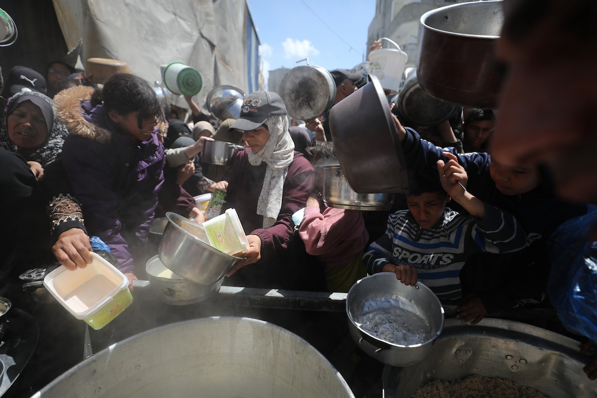 إحدى الجمعيات الخيرية توزع وجبات طعام على الفلسطينيين النازحين في مخيم النصيرات للاجئين، في ظل استمرار نقص الغذاء نتيجةً للسياسة الإسرائيلية المتعلقة بدخول المساعدات إلى مدينة غزة، في 11 أبريل/نيسان 2026. (تصوير: حسن جيدي)