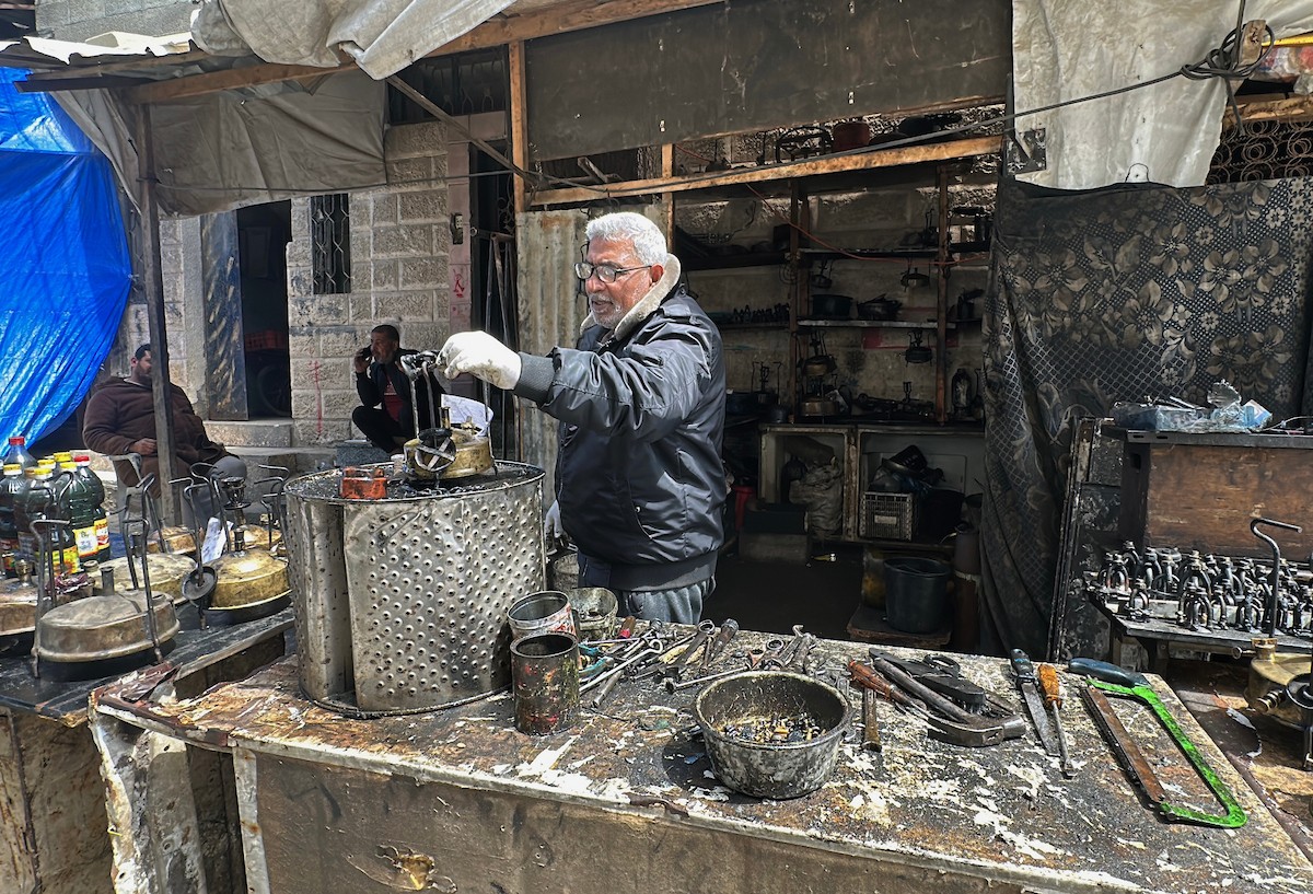 عادل عيسى، 63 عامًا، يُصلح مواقد الكيروسين القديمة في ورشته بمخيم الشاطئ، في مدينة غزة، صورة فوتوغرافية لهادي داود