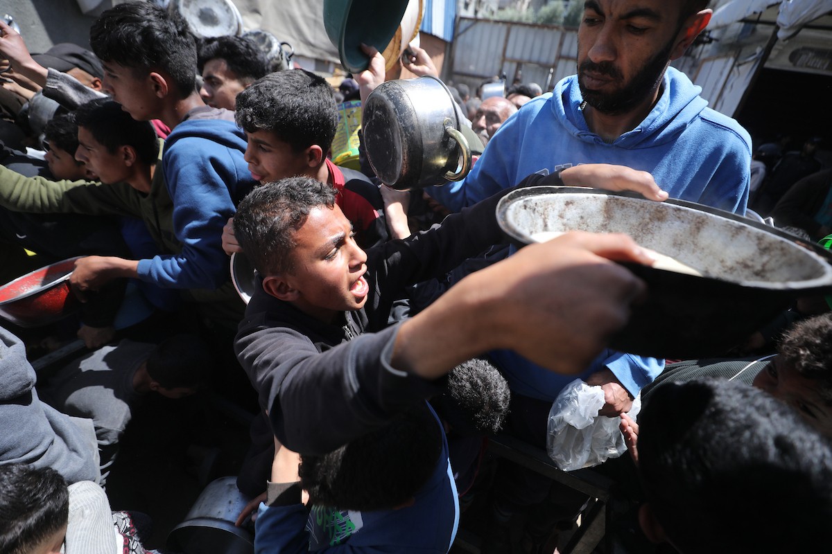 إحدى الجمعيات الخيرية توزع وجبات طعام على الفلسطينيين النازحين في مخيم النصيرات للاجئين، في ظل استمرار نقص الغذاء نتيجةً للسياسة الإسرائيلية المتعلقة بدخول المساعدات إلى مدينة غزة، في 11 أبريل/نيسان 2026. (تصوير: حسن جيدي)