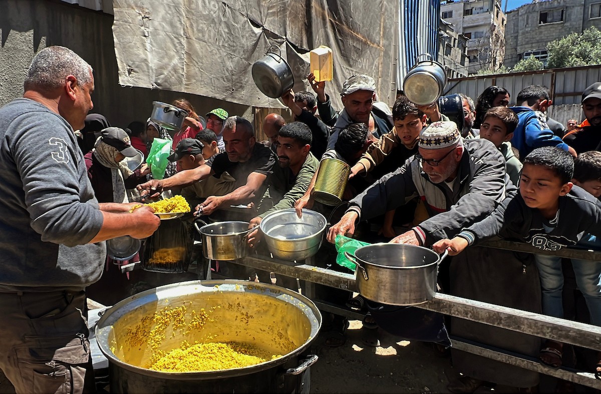 يتلقى فلسطينيون نازحون طعامًا من مطبخ خيري في مخيم النصيرات للاجئين وسط قطاع غزة، في 23 أبريل/نيسان 2026، (صورة: يوسف أبو وطفة)