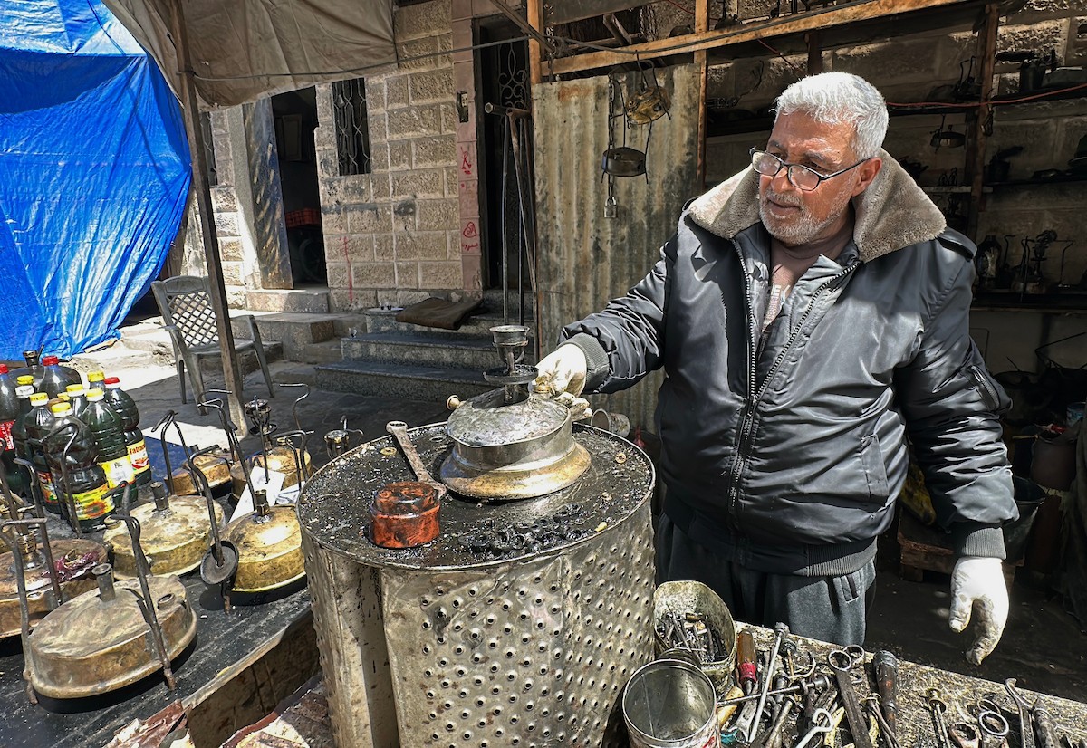 عادل عيسى، 63 عامًا، يُصلح مواقد الكيروسين القديمة في ورشته بمخيم الشاطئ، في مدينة غزة، صورة فوتوغرافية لهادي داود