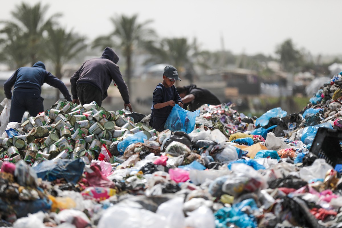 أطفال فلسطينيون يبحثون بين أكوام القمامة عن بقايا الطعام أو الألعاب في مكب نفايات بمخيم البريج للاجئين وسط قطاع غزة، في 4 أبريل/نيسان 2026، بالتزامن مع يوم الطفل الفلسطيني.(صورة: رمزي أبو عامر)