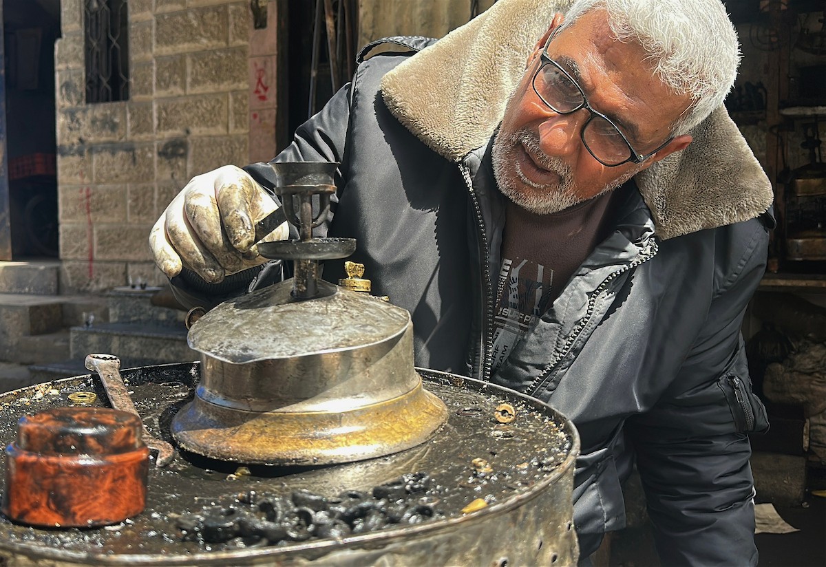 عادل عيسى، 63 عامًا، يُصلح مواقد الكيروسين القديمة في ورشته بمخيم الشاطئ، في مدينة غزة، صورة فوتوغرافية لهادي داود