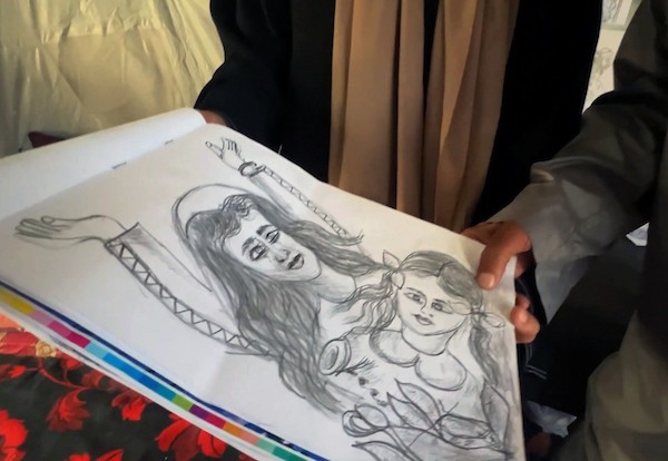 محمد زملط، رجل فلسطيني مسنّ اقتلعته الحرب من مخيم جباليا في شمال قطاع غزة، يحمل اليوم ريشته كوسيلة للبقاء، لا للفن فقط. في خيمته المتواضعة بمخيم البريج وسط القطاع، 12 أبريل/نيسان 2026، عدسة: يوسف أبو وطفة