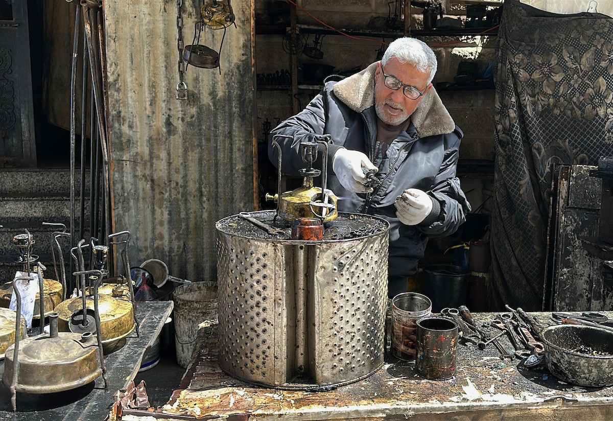 عادل عيسى، 63 عامًا، يُصلح مواقد الكيروسين القديمة في ورشته بمخيم الشاطئ، في مدينة غزة، صورة فوتوغرافية لهادي داود
