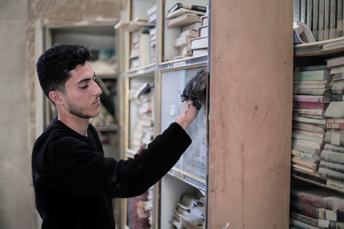يتردد الشاب الفلسطيني كريم الخضري على مكتبة الجامع الكبير بغزة (الجامع العمري) في البلدة القديمة، شرق مدينة غزة، حيث يقوم بتنظيف الكتب وترتيبها بجدٍّ واجتهاد، 26 أبريل/نيسان 2026. تصوير: محمد الأسود