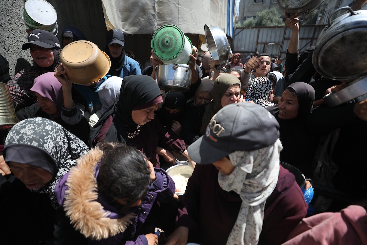 إحدى الجمعيات الخيرية توزع وجبات طعام على الفلسطينيين النازحين في مخيم النصيرات للاجئين، في ظل استمرار نقص الغذاء نتيجةً للسياسة الإسرائيلية المتعلقة بدخول المساعدات إلى مدينة غزة، في 11 أبريل/نيسان 2026. (تصوير: حسن جيدي)