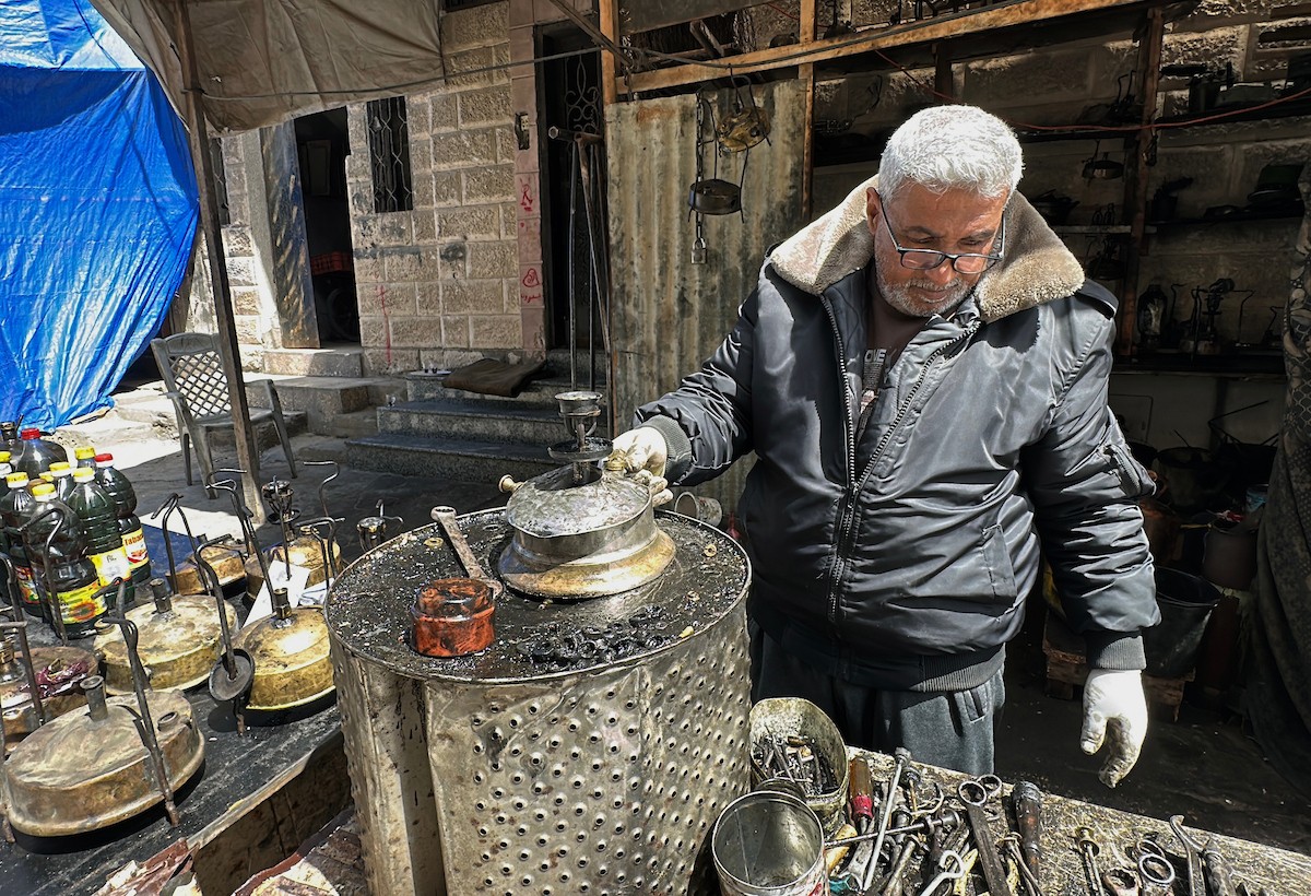 عادل عيسى، 63 عامًا، يُصلح مواقد الكيروسين القديمة في ورشته بمخيم الشاطئ، في مدينة غزة، صورة فوتوغرافية لهادي داود