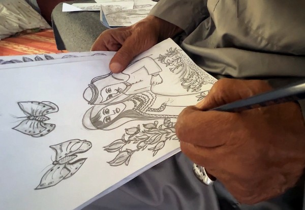 محمد زملط، رجل فلسطيني مسنّ اقتلعته الحرب من مخيم جباليا في شمال قطاع غزة، يحمل اليوم ريشته كوسيلة للبقاء، لا للفن فقط. في خيمته المتواضعة بمخيم البريج وسط القطاع، 12 أبريل/نيسان 2026، عدسة: يوسف أبو وطفة