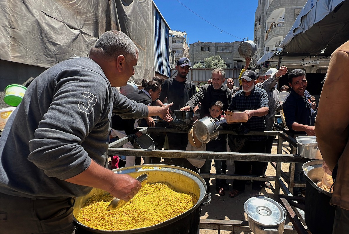 يتلقى فلسطينيون نازحون طعامًا من مطبخ خيري في مخيم النصيرات للاجئين وسط قطاع غزة، في 23 أبريل/نيسان 2026، (صورة: يوسف أبو وطفة)