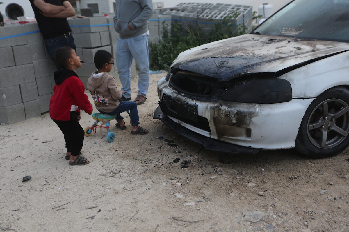 يقف فلسطينيون وسط آثار الدمار في قرية عورتا جنوب نابلس شمال الضفة الغربية، عقب هجوم نفذه مستوطنون إسرائيليون استهدف مركبات ومنازل المواطنين، مخلّفًا أضرارًا واسعة، وفق شهود عيان. 17 أبريل/نيسان 2026. تصوير: محمد ناصر.
