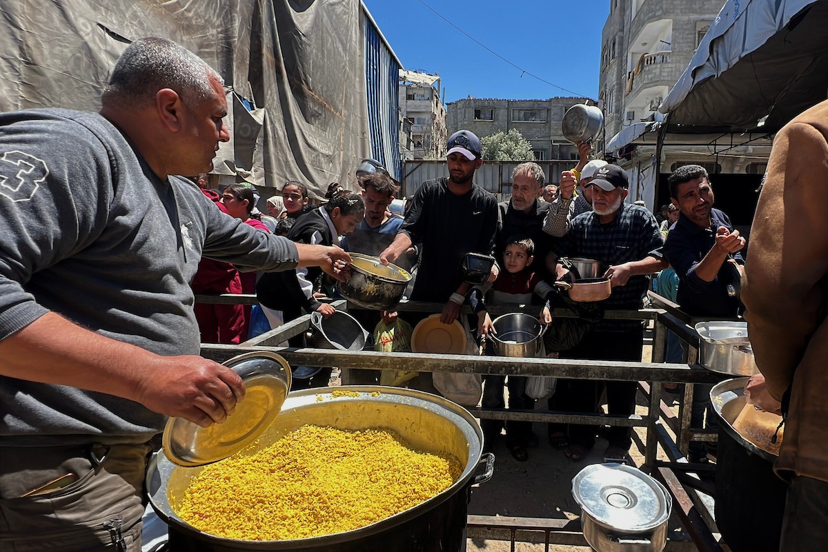 يتلقى فلسطينيون نازحون طعامًا من مطبخ خيري في مخيم النصيرات للاجئين وسط قطاع غزة، في 23 أبريل/نيسان 2026، (صورة: يوسف أبو وطفة)