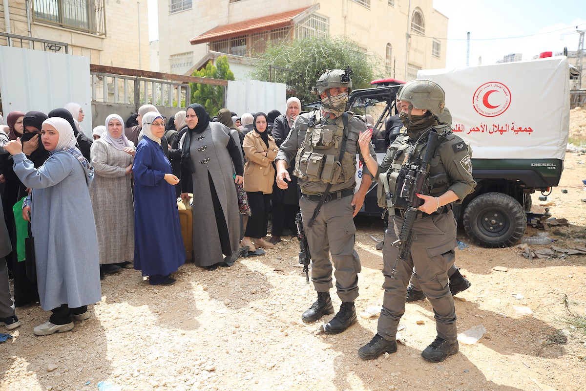 عائلات فلسطينية تنتظر عند نقطة تفتيش تابعة للجيش الإسرائيلي عند مدخل مخيم جنين للاجئين، قرب مدينة جنين في الضفة الغربية، لاستعادة ممتلكاتها من منازلها، 13 أبريل/نيسان 2026. صورة: محمد ناصر