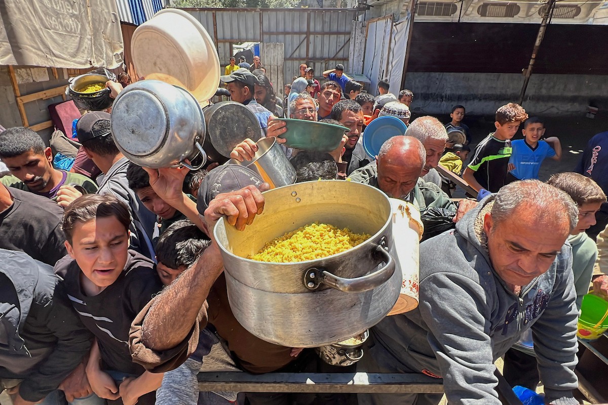يتلقى فلسطينيون نازحون طعامًا من مطبخ خيري في مخيم النصيرات للاجئين وسط قطاع غزة، في 23 أبريل/نيسان 2026، (صورة: يوسف أبو وطفة)