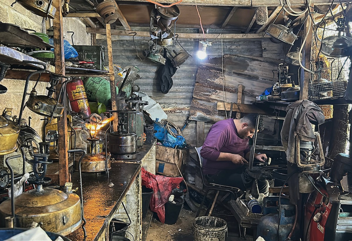 عادل عيسى، 63 عامًا، يُصلح مواقد الكيروسين القديمة في ورشته بمخيم الشاطئ، في مدينة غزة، صورة فوتوغرافية لهادي داود