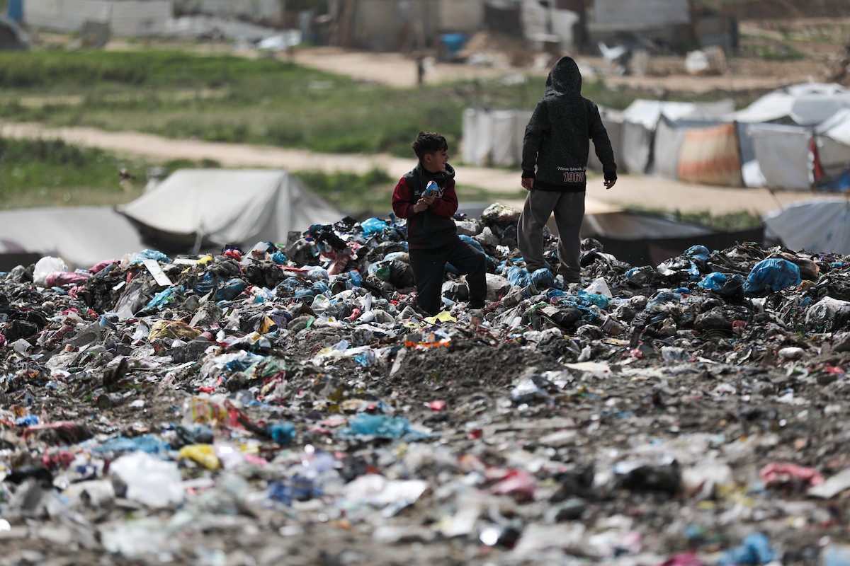 أطفال فلسطينيون يبحثون بين أكوام القمامة عن بقايا الطعام أو الألعاب في مكب نفايات بمخيم البريج للاجئين وسط قطاع غزة، في 4 أبريل/نيسان 2026، بالتزامن مع يوم الطفل الفلسطيني.(صورة: رمزي أبو عامر)