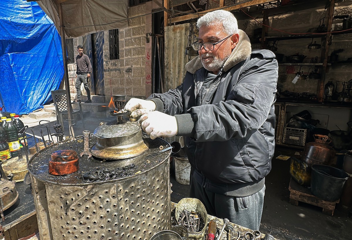 عادل عيسى، 63 عامًا، يُصلح مواقد الكيروسين القديمة في ورشته بمخيم الشاطئ، في مدينة غزة، صورة فوتوغرافية لهادي داود