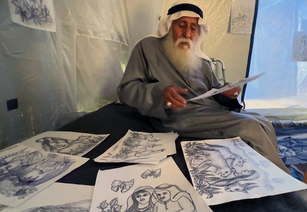 محمد زملط، رجل فلسطيني مسنّ اقتلعته الحرب من مخيم جباليا في شمال قطاع غزة، يحمل اليوم ريشته كوسيلة للبقاء، لا للفن فقط. في خيمته المتواضعة بمخيم البريج وسط القطاع، 12 أبريل/نيسان 2026، عدسة: يوسف أبو وطفة