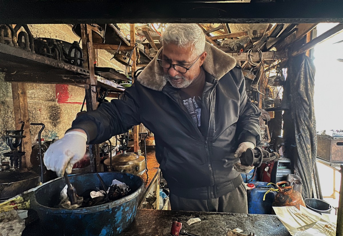 عادل عيسى، 63 عامًا، يُصلح مواقد الكيروسين القديمة في ورشته بمخيم الشاطئ، في مدينة غزة، صورة فوتوغرافية لهادي داود