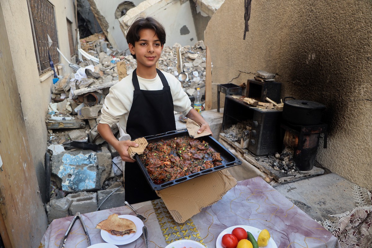 ياسر عياد، فتى فلسطيني يبلغ من العمر أربعة عشر عامًا، يمارس مهاراته في الطبخ على نار الحطب بجوار أنقاض منزل عائلته المدمر في مدينة غزة. غزة، 10 أبريل/نيسان 2026. تصوير: محمد الأسود