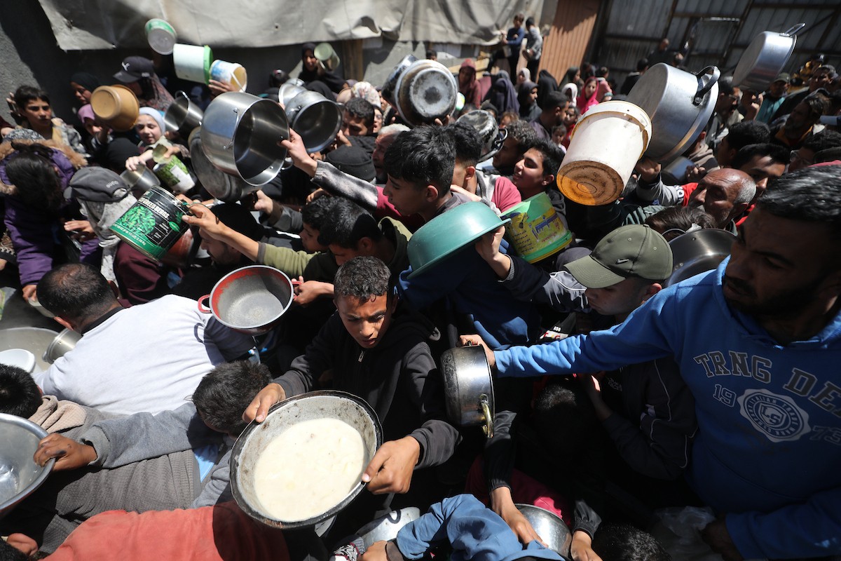 إحدى الجمعيات الخيرية توزع وجبات طعام على الفلسطينيين النازحين في مخيم النصيرات للاجئين، في ظل استمرار نقص الغذاء نتيجةً للسياسة الإسرائيلية المتعلقة بدخول المساعدات إلى مدينة غزة، في 11 أبريل/نيسان 2026. (تصوير: حسن جيدي)