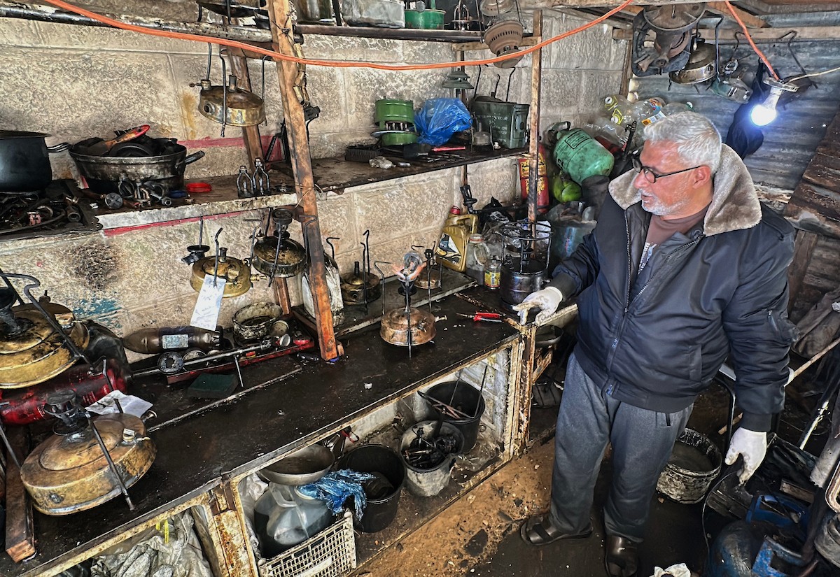 عادل عيسى، 63 عامًا، يُصلح مواقد الكيروسين القديمة في ورشته بمخيم الشاطئ، في مدينة غزة، صورة فوتوغرافية لهادي داود