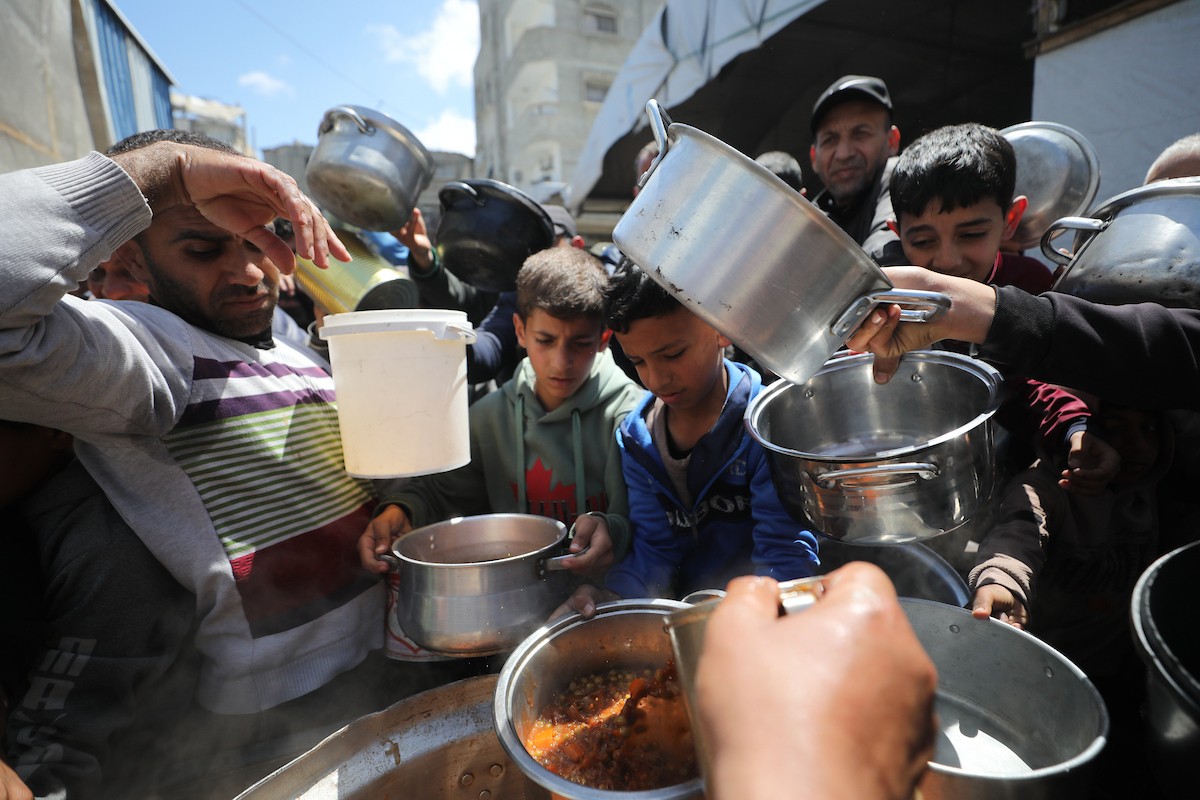 إحدى الجمعيات الخيرية توزع وجبات طعام على الفلسطينيين النازحين في مخيم النصيرات للاجئين، في ظل استمرار نقص الغذاء نتيجةً للسياسة الإسرائيلية المتعلقة بدخول المساعدات إلى مدينة غزة، في 11 أبريل/نيسان 2026. (تصوير: حسن جيدي)
