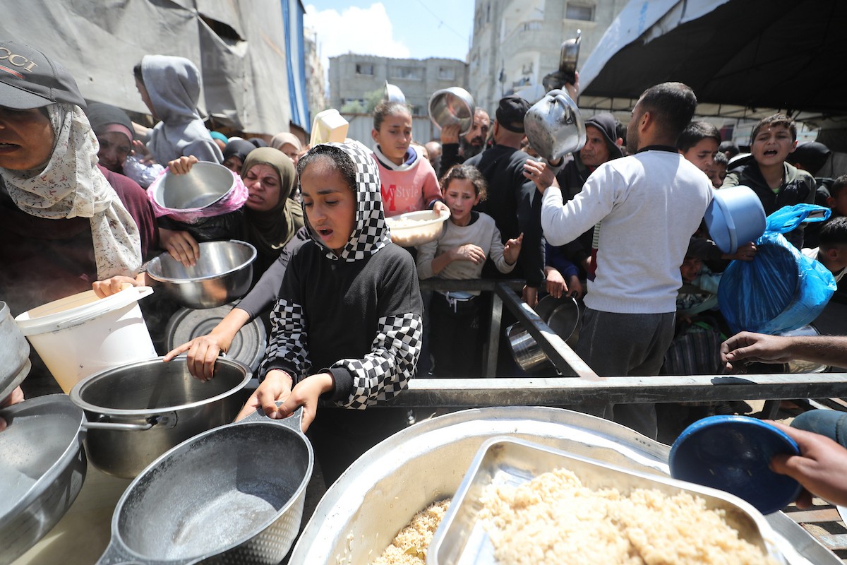 إحدى الجمعيات الخيرية توزع وجبات طعام على الفلسطينيين النازحين في مخيم النصيرات للاجئين، في ظل استمرار نقص الغذاء نتيجةً للسياسة الإسرائيلية المتعلقة بدخول المساعدات إلى مدينة غزة، في 11 أبريل/نيسان 2026. (تصوير: حسن جيدي)