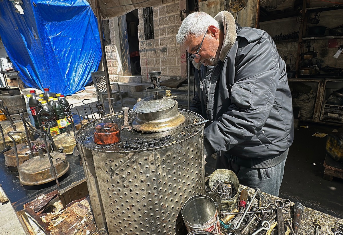 عادل عيسى، 63 عامًا، يُصلح مواقد الكيروسين القديمة في ورشته بمخيم الشاطئ، في مدينة غزة، صورة فوتوغرافية لهادي داود