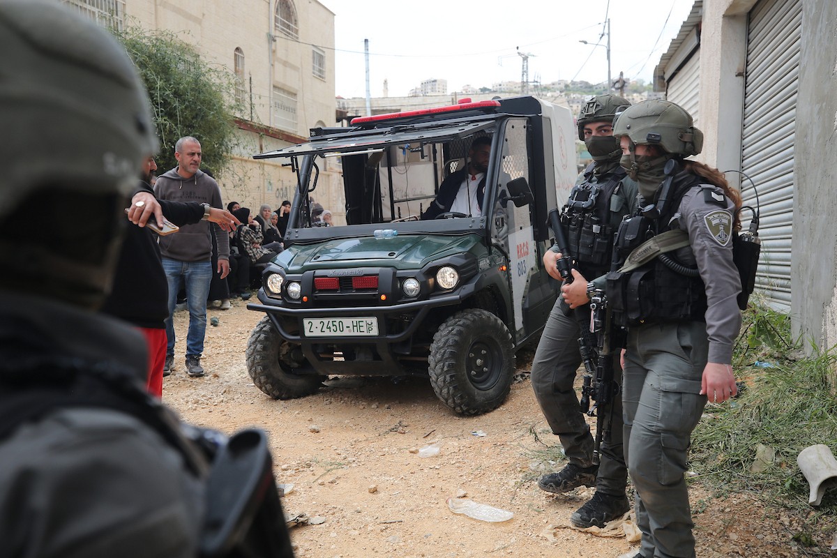 عائلات فلسطينية تنتظر عند نقطة تفتيش تابعة للجيش الإسرائيلي عند مدخل مخيم جنين للاجئين، قرب مدينة جنين في الضفة الغربية، لاستعادة ممتلكاتها من منازلها، 13 أبريل/نيسان 2026. صورة: محمد ناصر