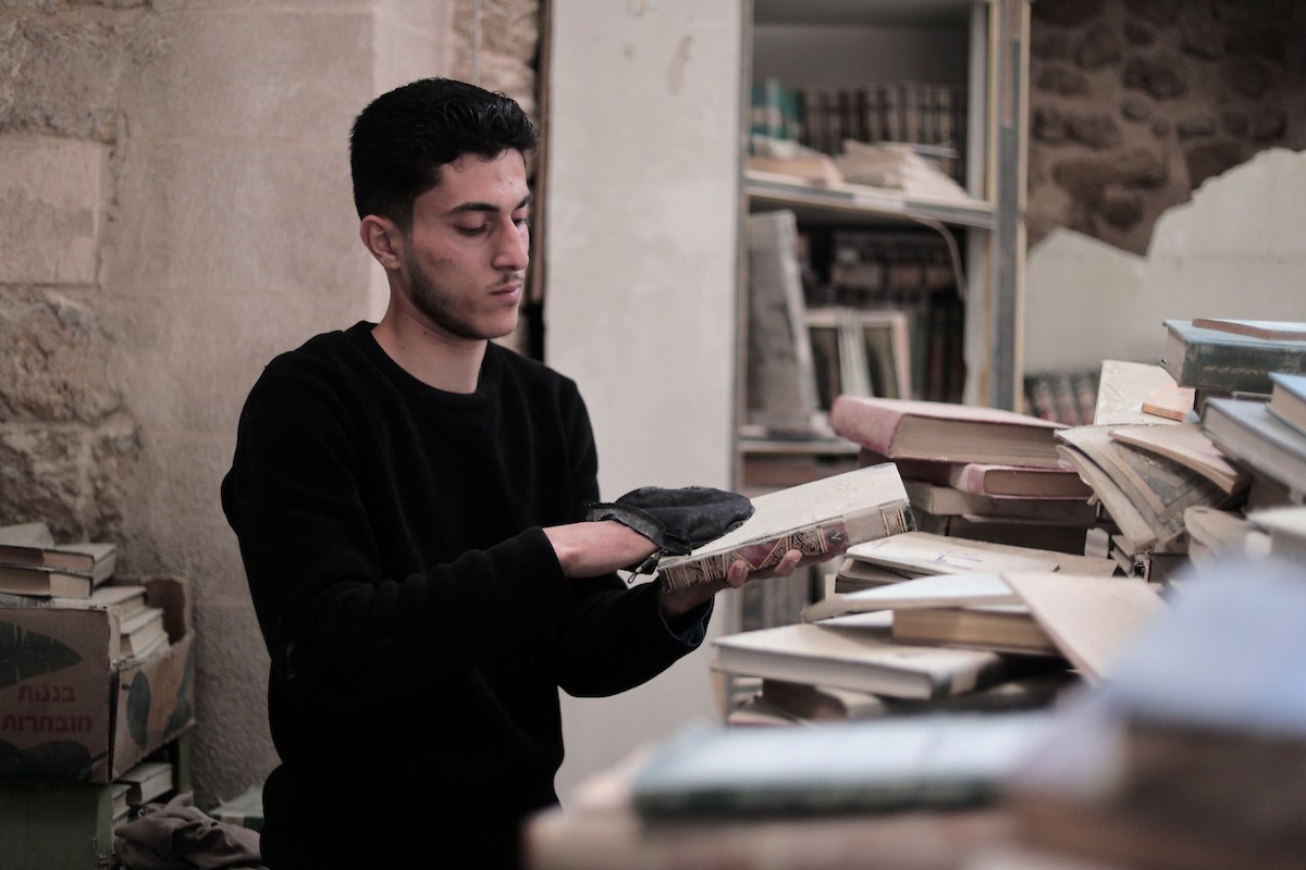 يتردد الشاب الفلسطيني كريم الخضري على مكتبة الجامع الكبير بغزة (الجامع العمري) في البلدة القديمة، شرق مدينة غزة، حيث يقوم بتنظيف الكتب وترتيبها بجدٍّ واجتهاد، 26 أبريل/نيسان 2026. تصوير: محمد الأسود
