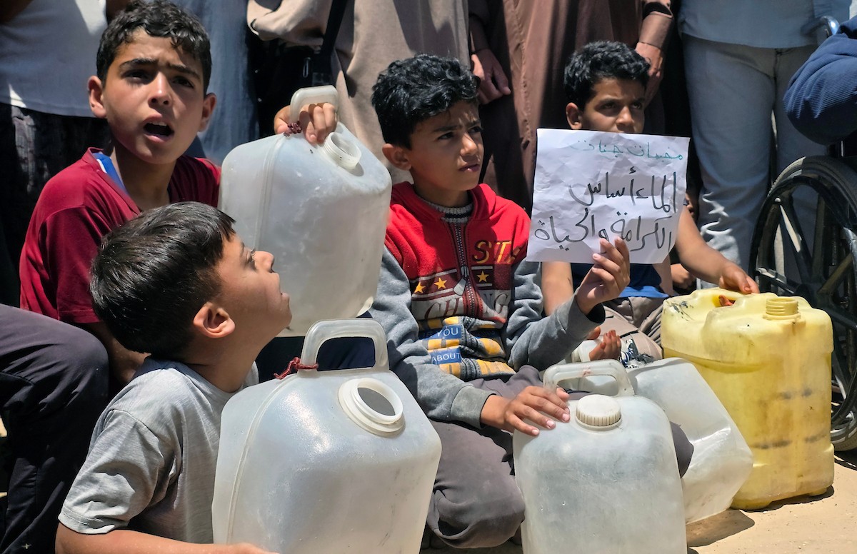 فلسطينيون نازحون يحملون عبوات مياه فارغة خلال احتجاج للمطالبة بتوفير مياه شرب آمنة في خان يونس جنوب قطاع غزة، 25 مايو/أيار 2026. تصوير: طارق محمد
