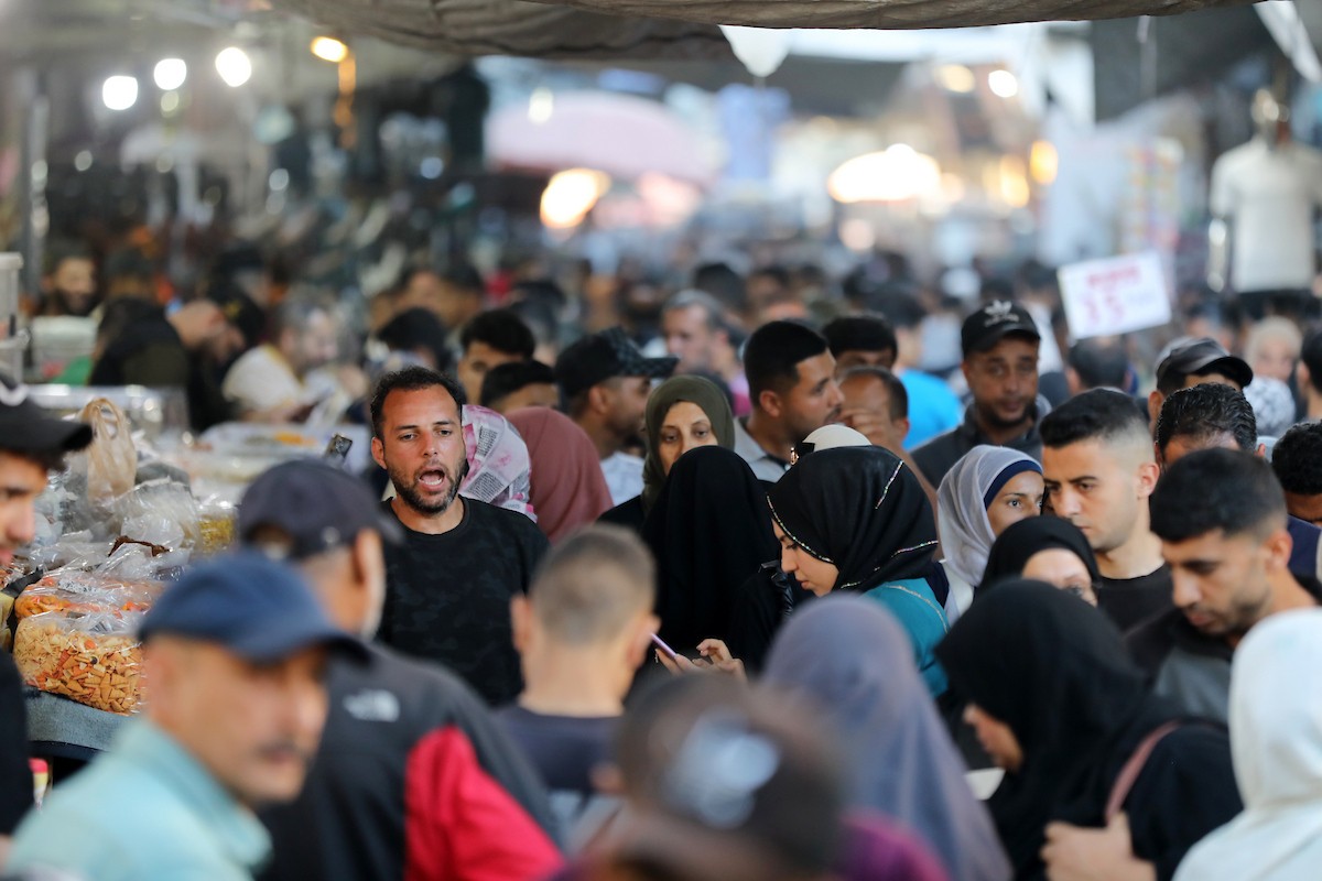 فلسطينيون يتجولون في سوق عمر المختار بمدينة غزة، حيث يعرض الباعة بضائعهم على أكشاك مؤقتة قبيل عيد الأضحى، وسط ضعف في الطلب وتراجع القدرة الشرائية، 25 مايو/أيار 2026. تصوير: بلال أسامة