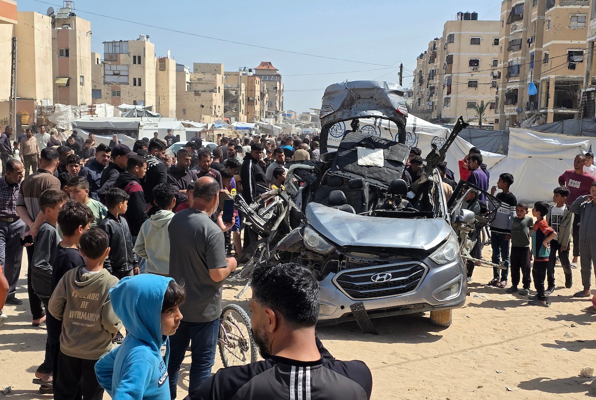 تُظهر الصورة فلسطينيين يتفقدون آثار غارة إسرائيلية استهدفت مركبة في خان يونس، جنوب قطاع غزة، حيث تحولت المركبة إلى حطام، فيما واصل الأهالي التجمع في المكان وسط حالة من الصدمة والغضب، 10 أيار/ مايو 2026.(صورة: طارق محمد)