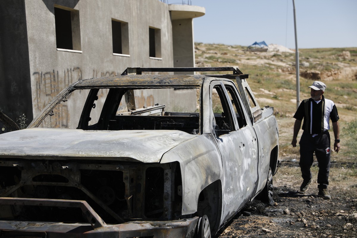 يتفقد فلسطينيون مركبةً تضررت بعد أن أضرم فيها مستوطنون إسرائيليون النار في وادي الرحيم قرب بلدة يطا، جنوب الخليل في الضفة الغربية، في الأول من مايو/أيار 2026.(صورة: مأمون وزواز)