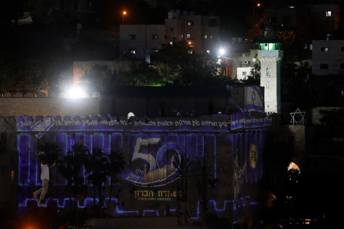 مستعمرون إسرائيليون يشاركون في فعاليات احتفالية بمحيط الحرم الإبراهيمي في مدينة الخليل، حيث رُفعت الأعلام الإسرائيلية ورموز نجمة داود على واجهاته، وسط إجراءات أمنية مشددة، يوم 19 مايو/أيار 2026. تصوير: مأمون وزواز