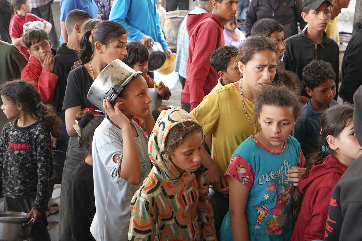 فلسطينيون نازحون، بينهم نساء وأطفال، يتجمعون لتلقي وجبات طعام من مطبخ خيري في مخيم النصيرات للاجئين وسط قطاع غزة، في 21 مايو/أيار 2026. الصورة: رمزي أبو عامر.